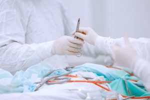 A nurse hands a scalpel to a surgeon in white scrubs who is about to perform unnecessary surgery