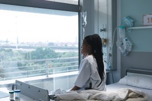 A patient sitting on a hospital bed and awaiting treatment for the serious consequences of her wrong diagnosis