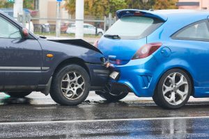 A rear-end collision between a navy car and a baby blue car.