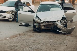 The front of a grey car completely damaged with the two passenger doors open.