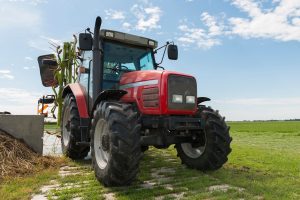 A red tracter with a nearby tedder. 