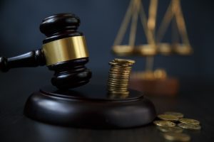 Coins stacked on top of a gavel to represent sexual abuse compensation.